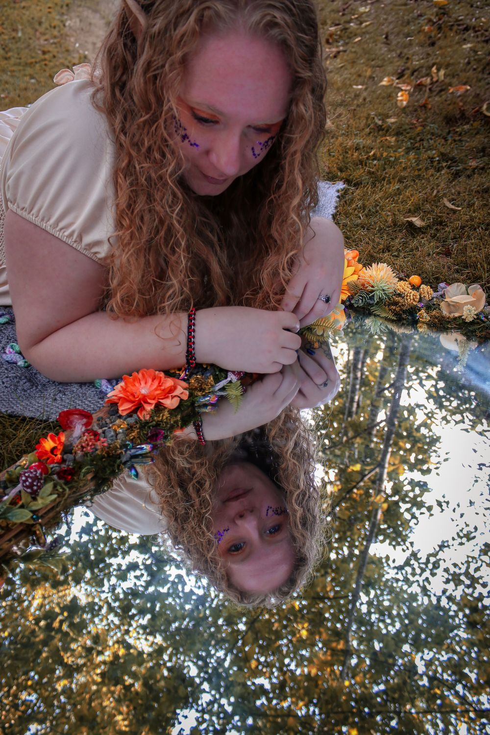 Creative mirror reflection photography with orange flowers and curly hair against a golden background.