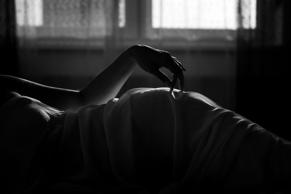 Silhouetted hand against backlit window in moody black and white composition.