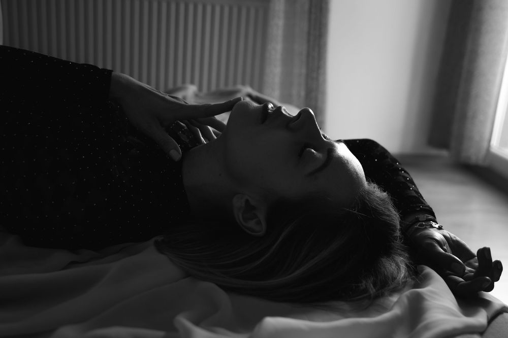 Artistic black and white portrait showing dramatic side lighting and shadows.