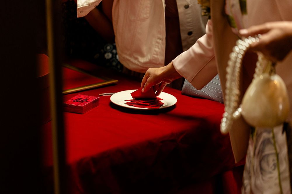 Hand placing a red item on a plate with elegant table setting and red tablecloth.