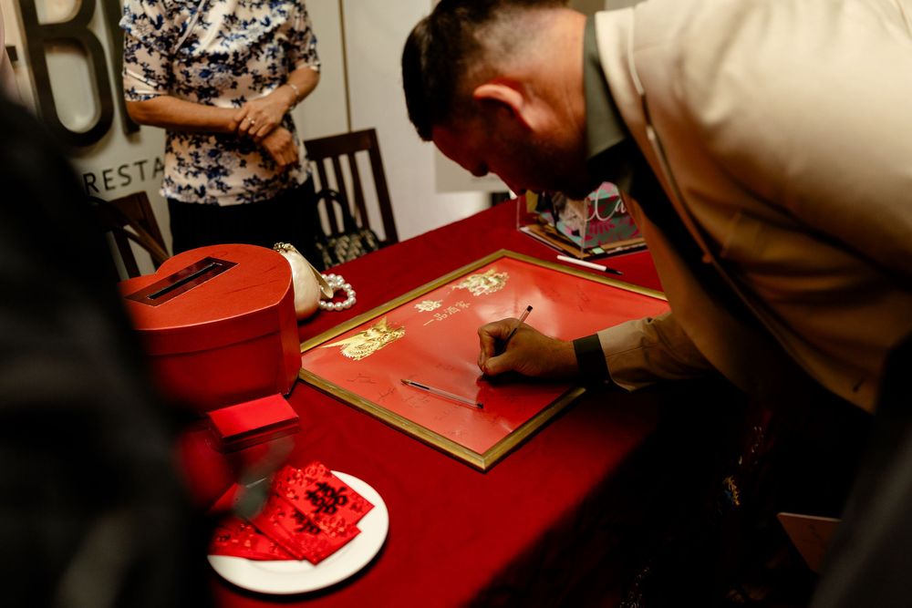 Person signing a red guest book at an event reception.