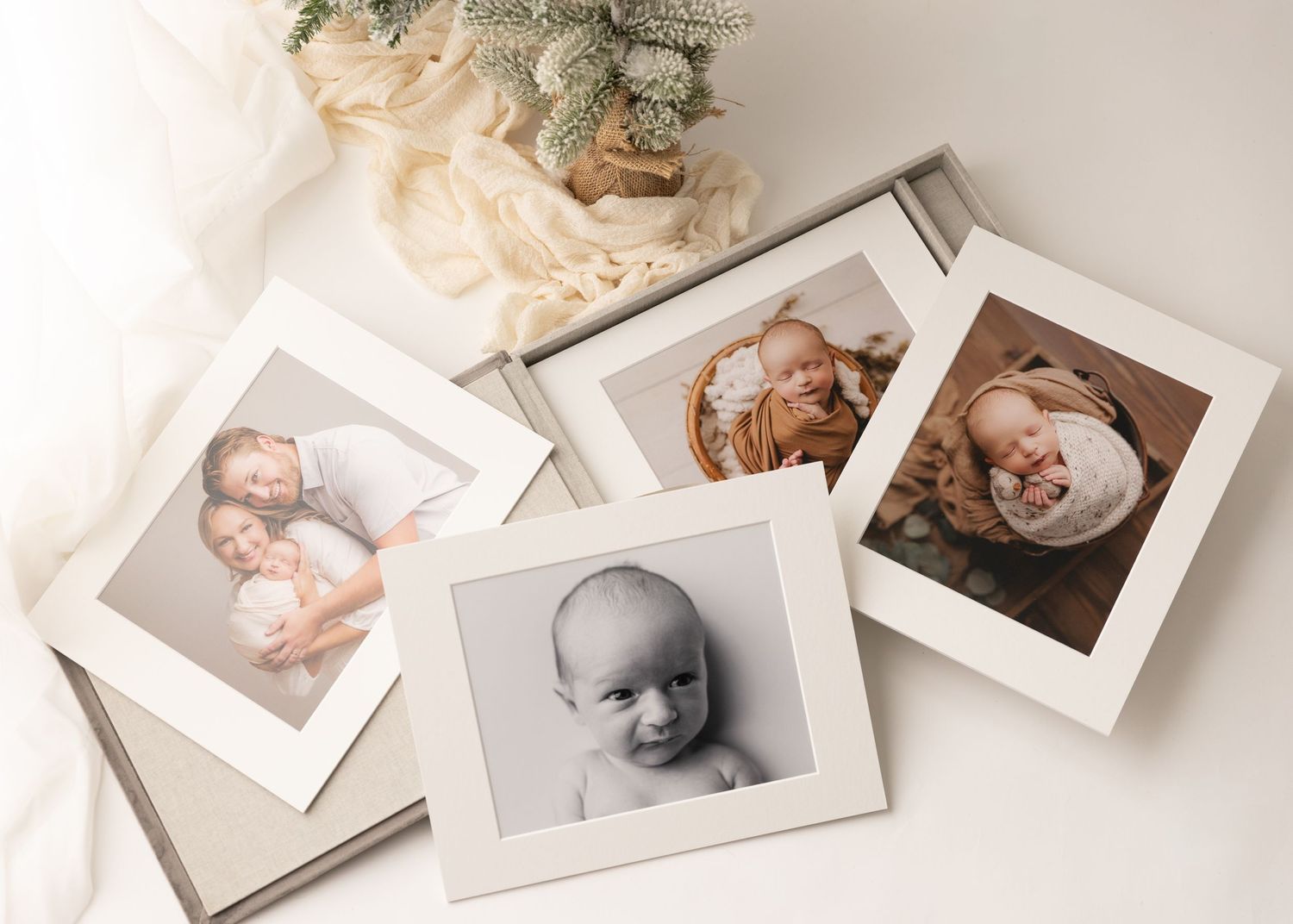 Several vintage-style portrait photographs in white frames arranged on a light neutral surface with soft decorative elements. MI studio