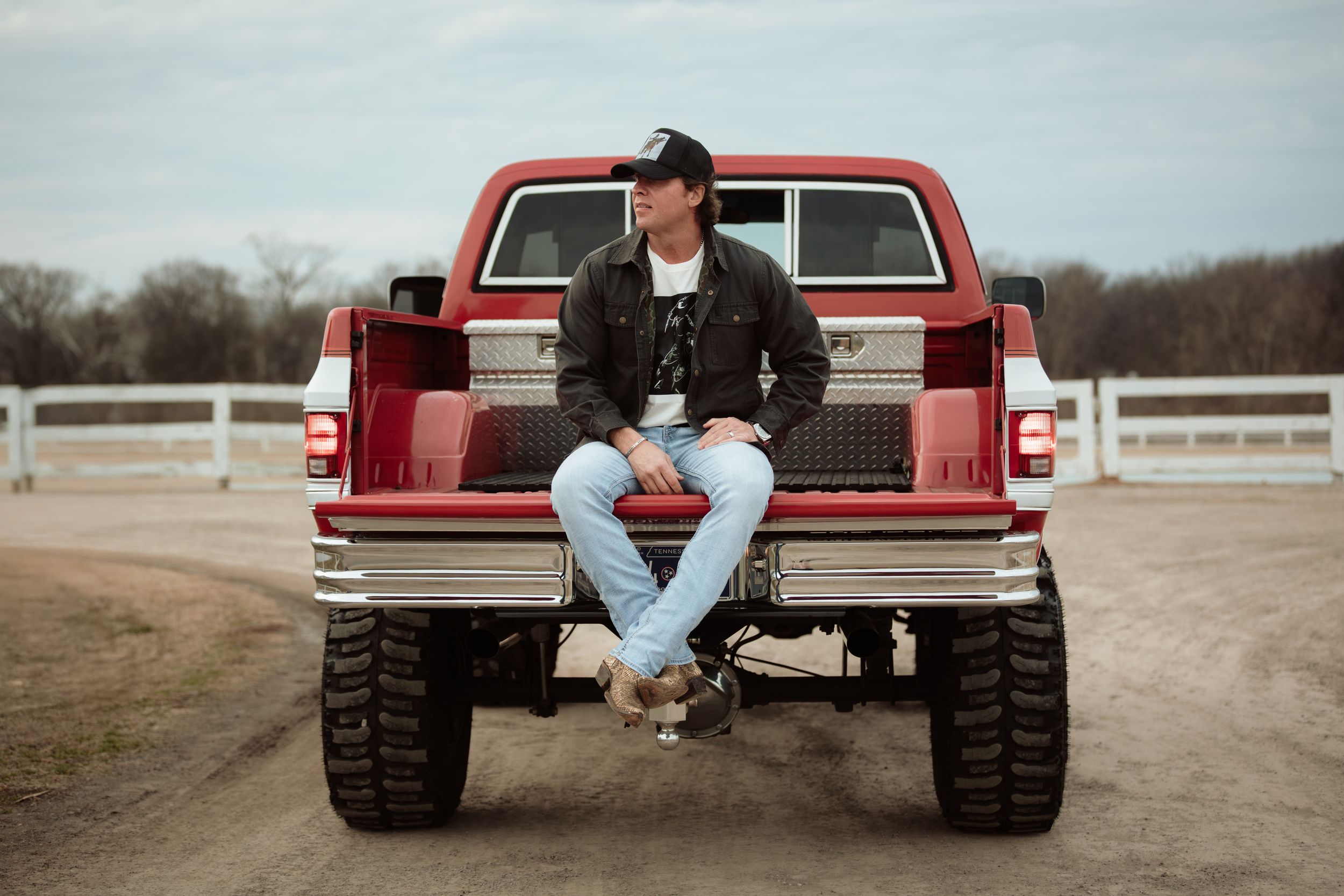 A red pickup truck with large off-road tires is shown in multiple angles parked on a dirt path.