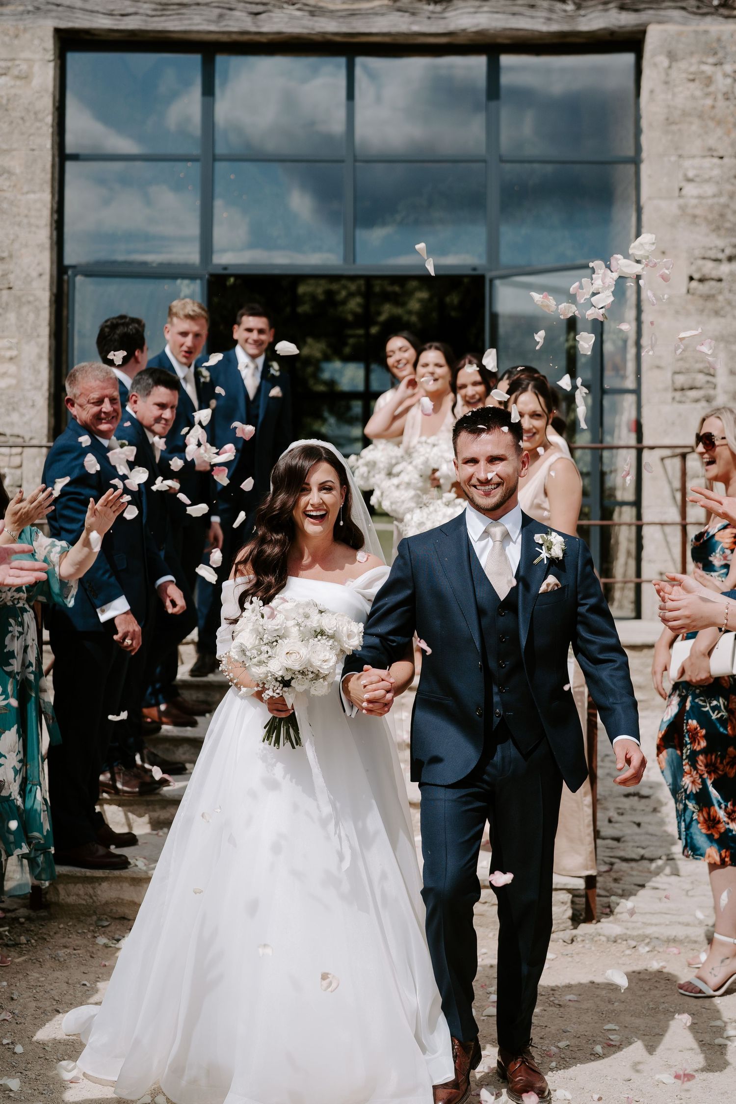 bride and groom walking though confetti throw at yardspace old gore in cirencester