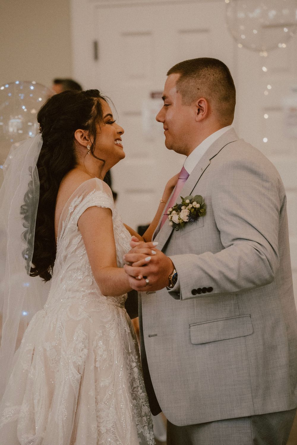 A tender moment between newlyweds dancing at their wedding reception with twinkle lights in the background.