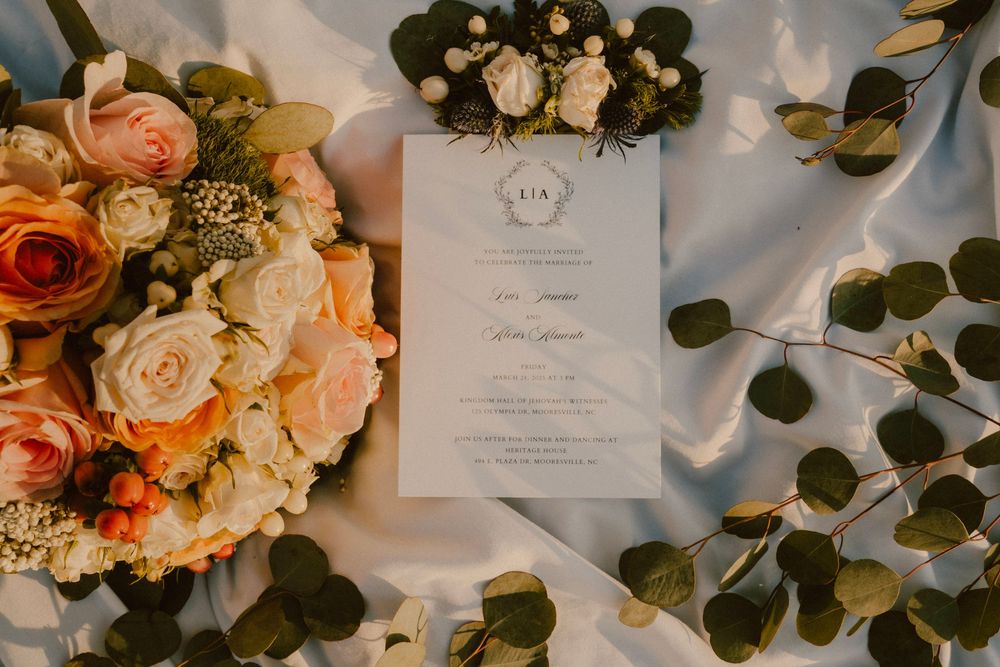 Wedding invitation surrounded by a beautiful peach and cream floral bouquet with eucalyptus leaves.