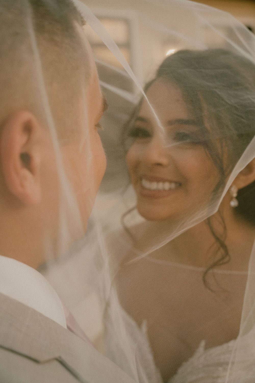 Intimate moment shared between newlyweds under a delicate white veil.