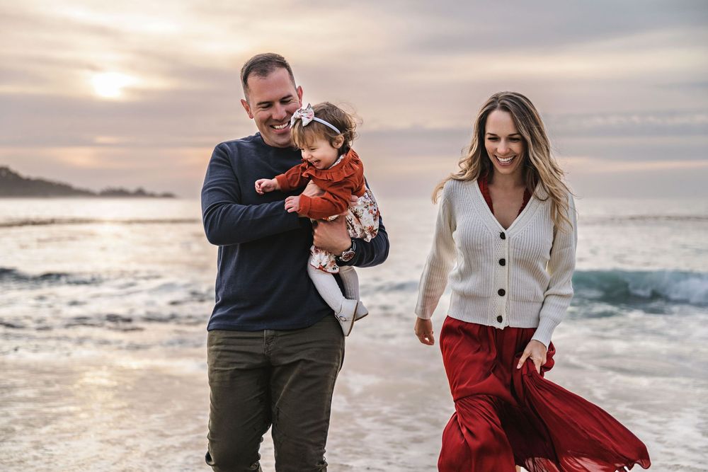 Family moment captured during sunset at rocky coastal beach.