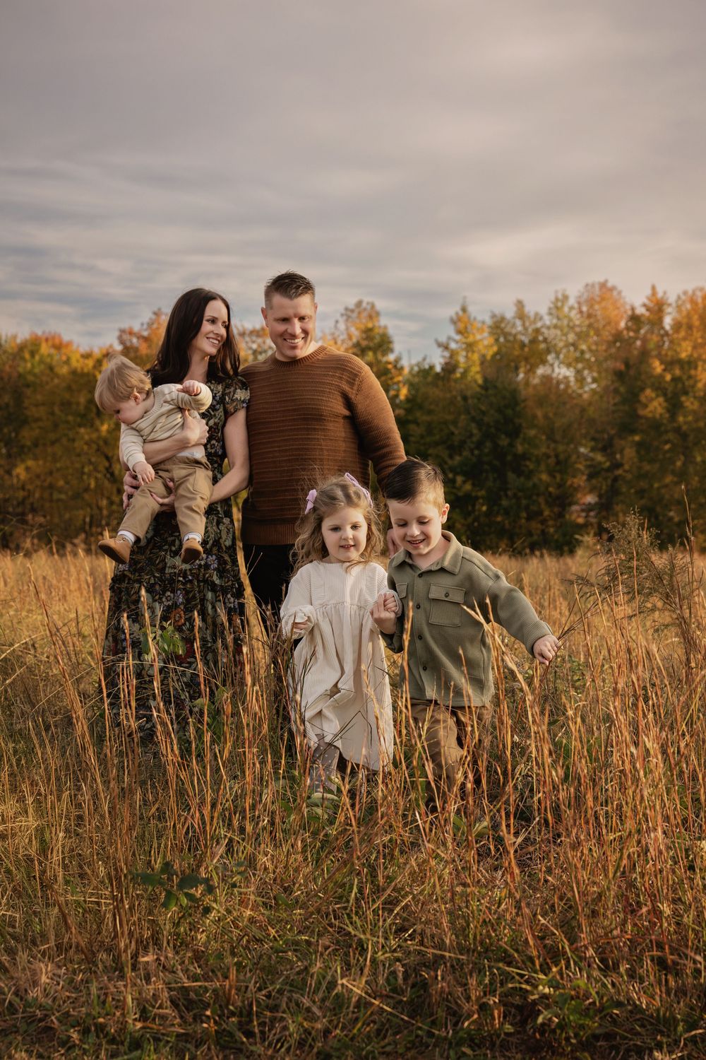 A family enjoys a tender moment together in a golden autumn field at sunset.