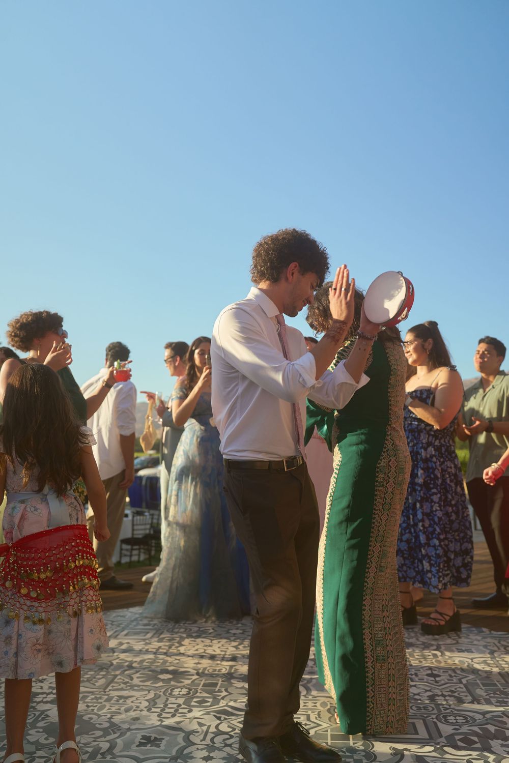 Couple sharing an intimate moment with a tambourine during an outdoor wedding dance celebration.