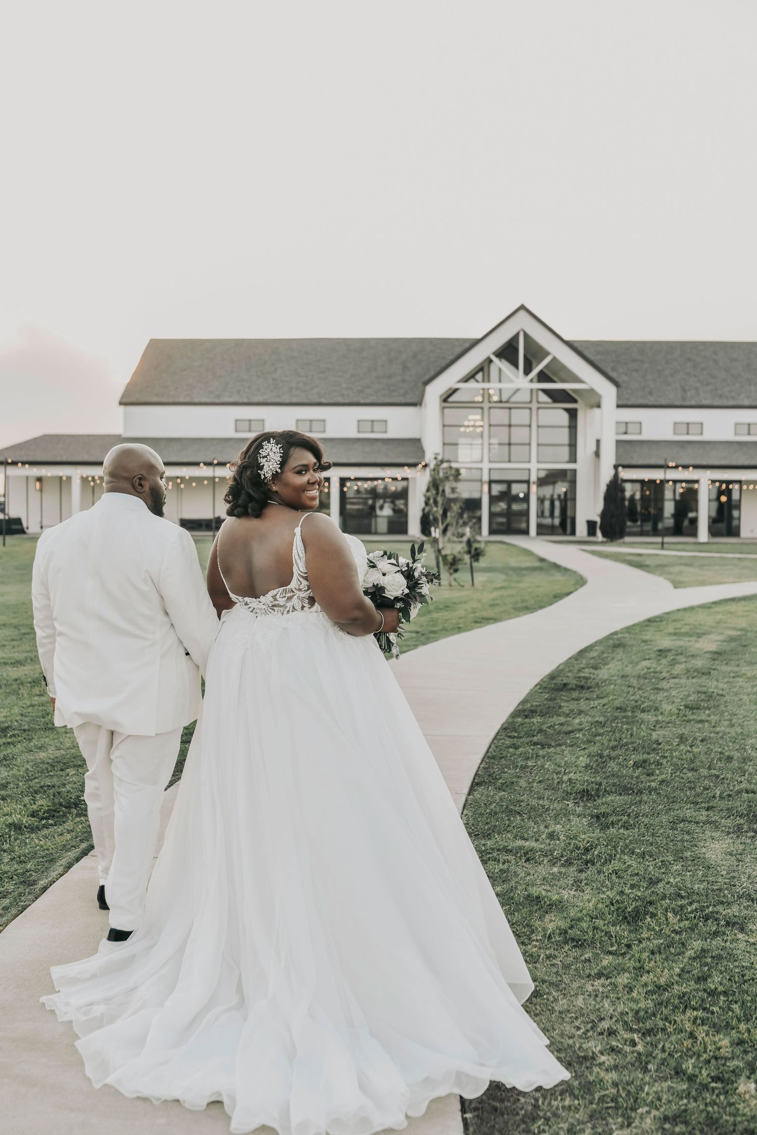 a beautiful bride and groom walk in the sunset towards their reception hall at the gardenia