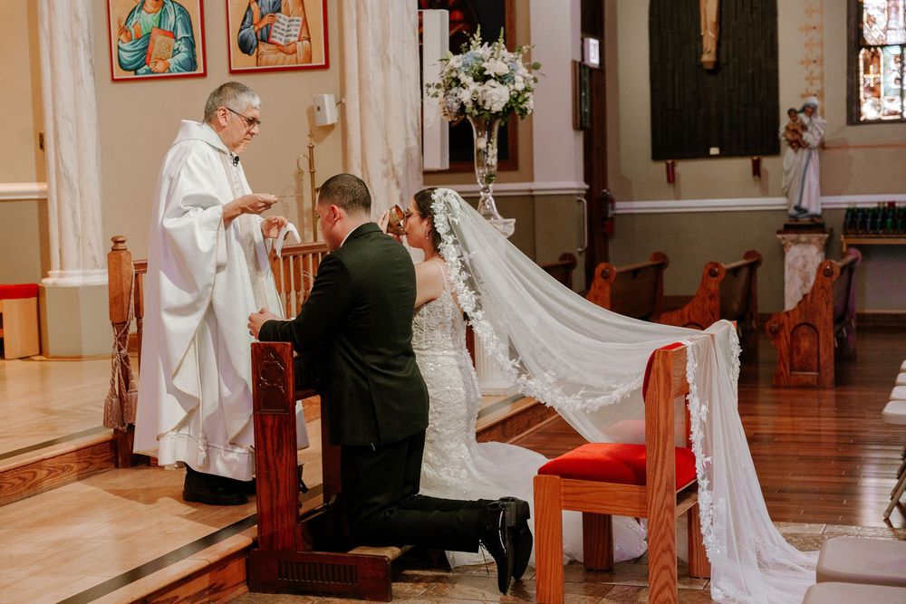 Wedding ceremony taking place in a traditional church with stained glass windows and wooden pews.