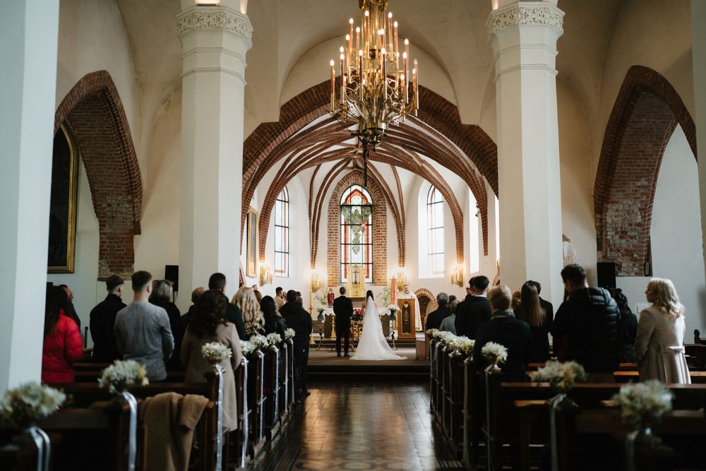 Elegant church interior with chandeliers and gothic arches during a wedding ceremony.