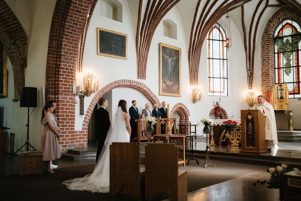 Interior of a gothic church with vaulted ceilings and arched windows during a wedding ceremony.