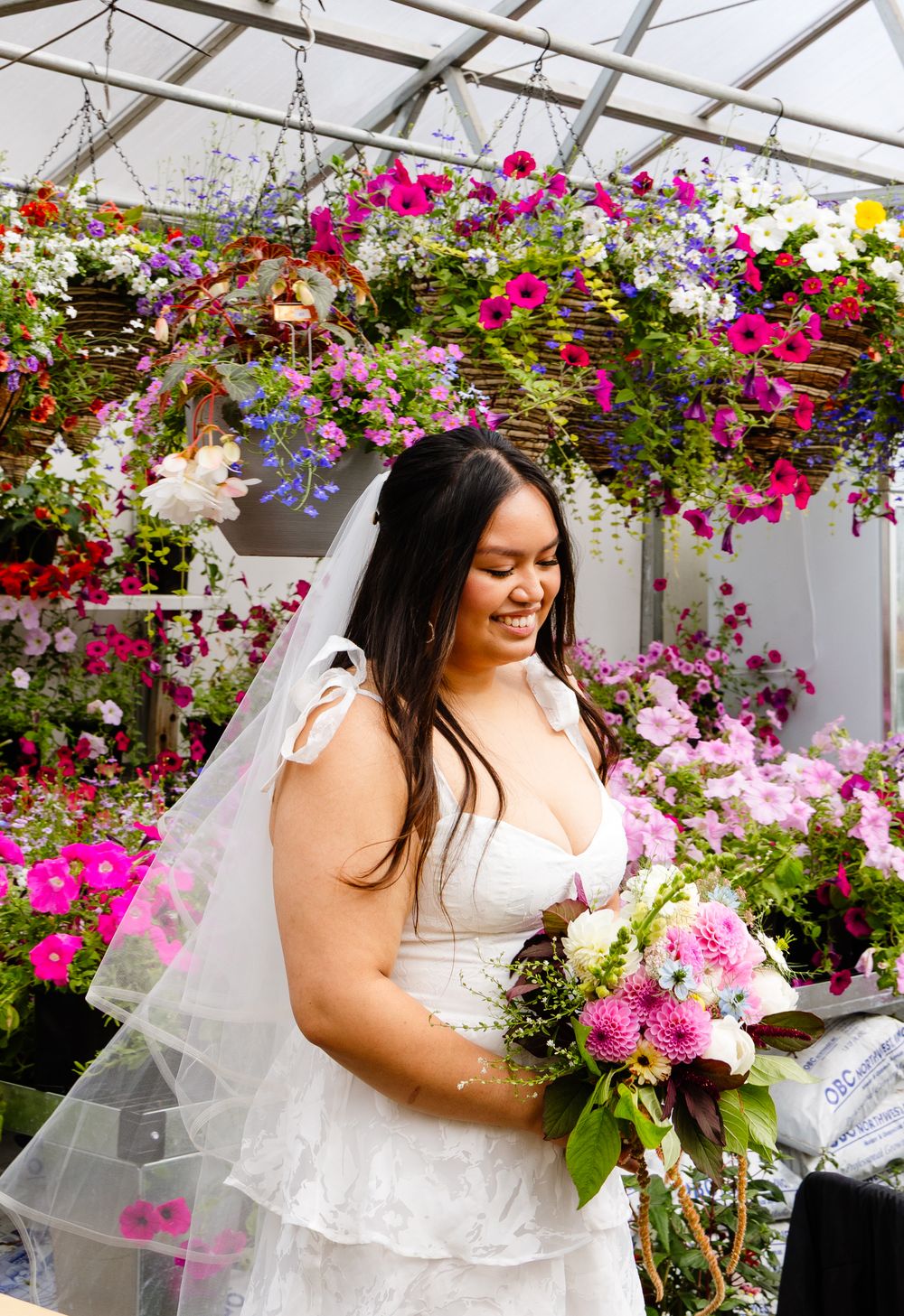 Stunning bridal photos in a greenhouse with vibrant pink bougainvillea flowers and white wedding dress.