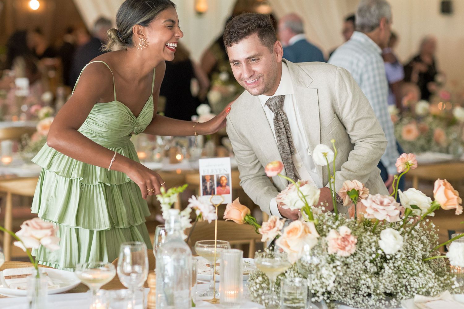 Wedding reception centerpieces feature white baby's breath and greenery with glowing candles on elegant dining tables.
