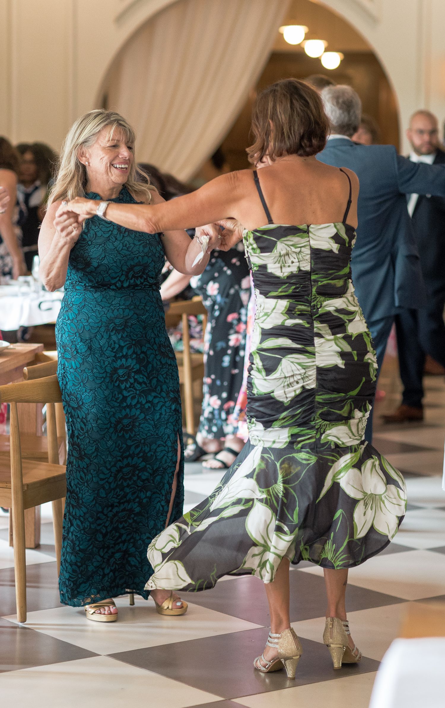 Guests in formal attire mingle and pose during a wedding reception in an elegant arched venue.