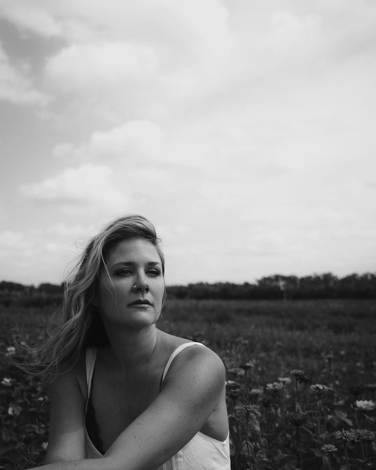 Artistic black and white portrait series in a natural field setting with moody clouds.