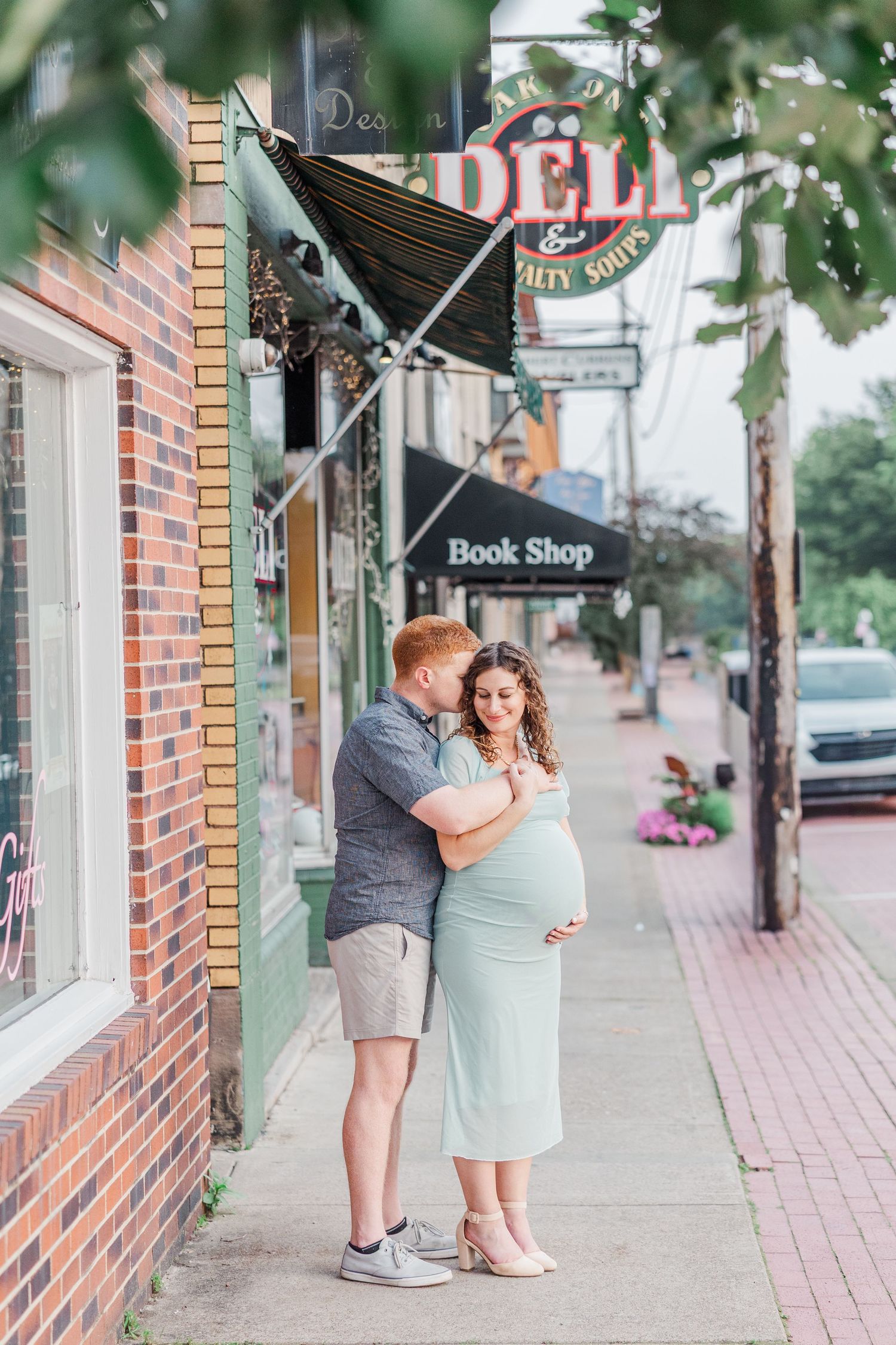 A couple poses playfully outside a bookshop during their maternity photoshoot.