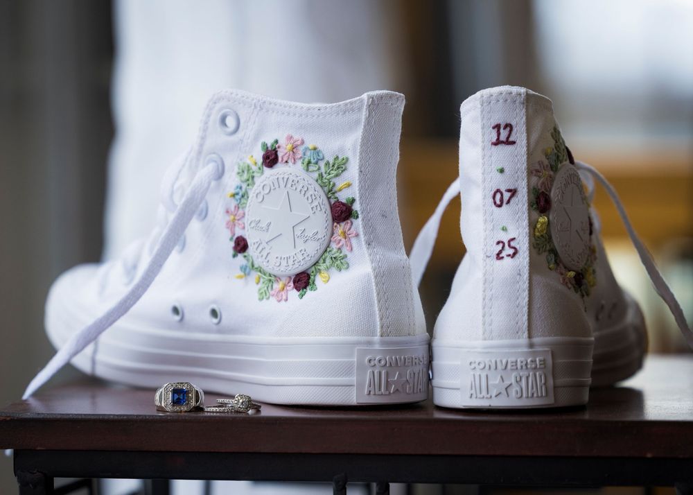 Custom decorated white wedding sneakers lined up in a row.
