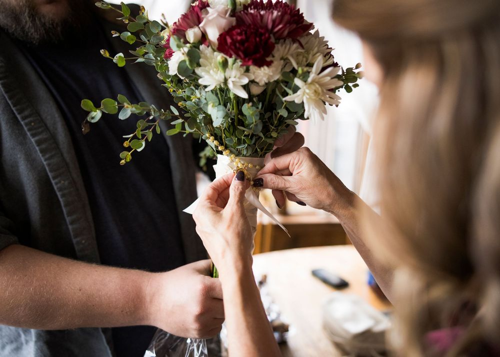 Close-up view of delicate pink and burgundy floral arrangements being assembled with greenery.