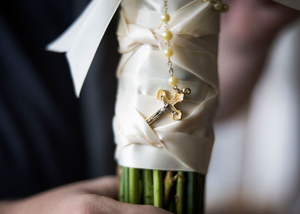 Close up of bridal bouquet wrapped in white ribbon with delicate details.