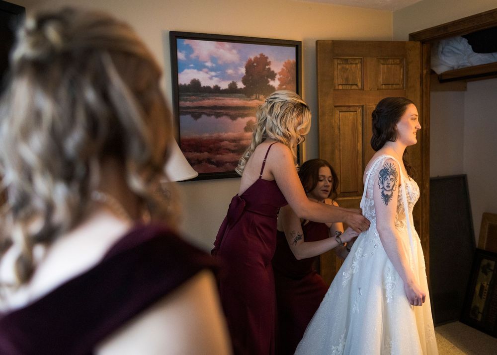 Wedding preparations showing dress and bridesmaids getting ready in a room.