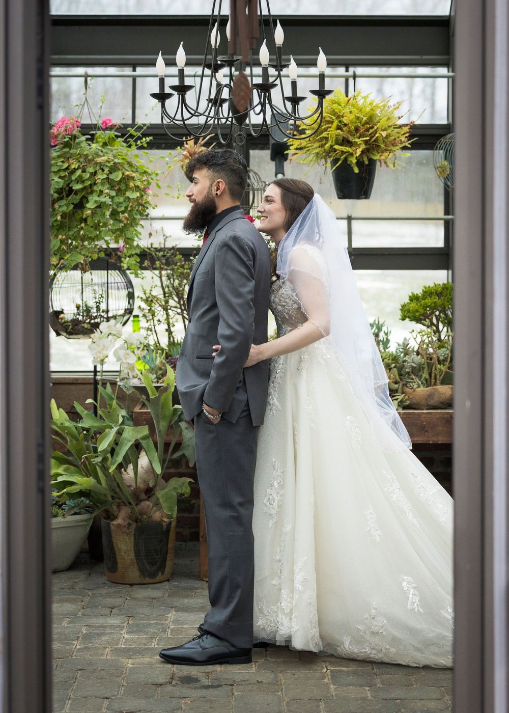 Bride and groom share a first look moment in a greenhouse filled with plants and natural light.