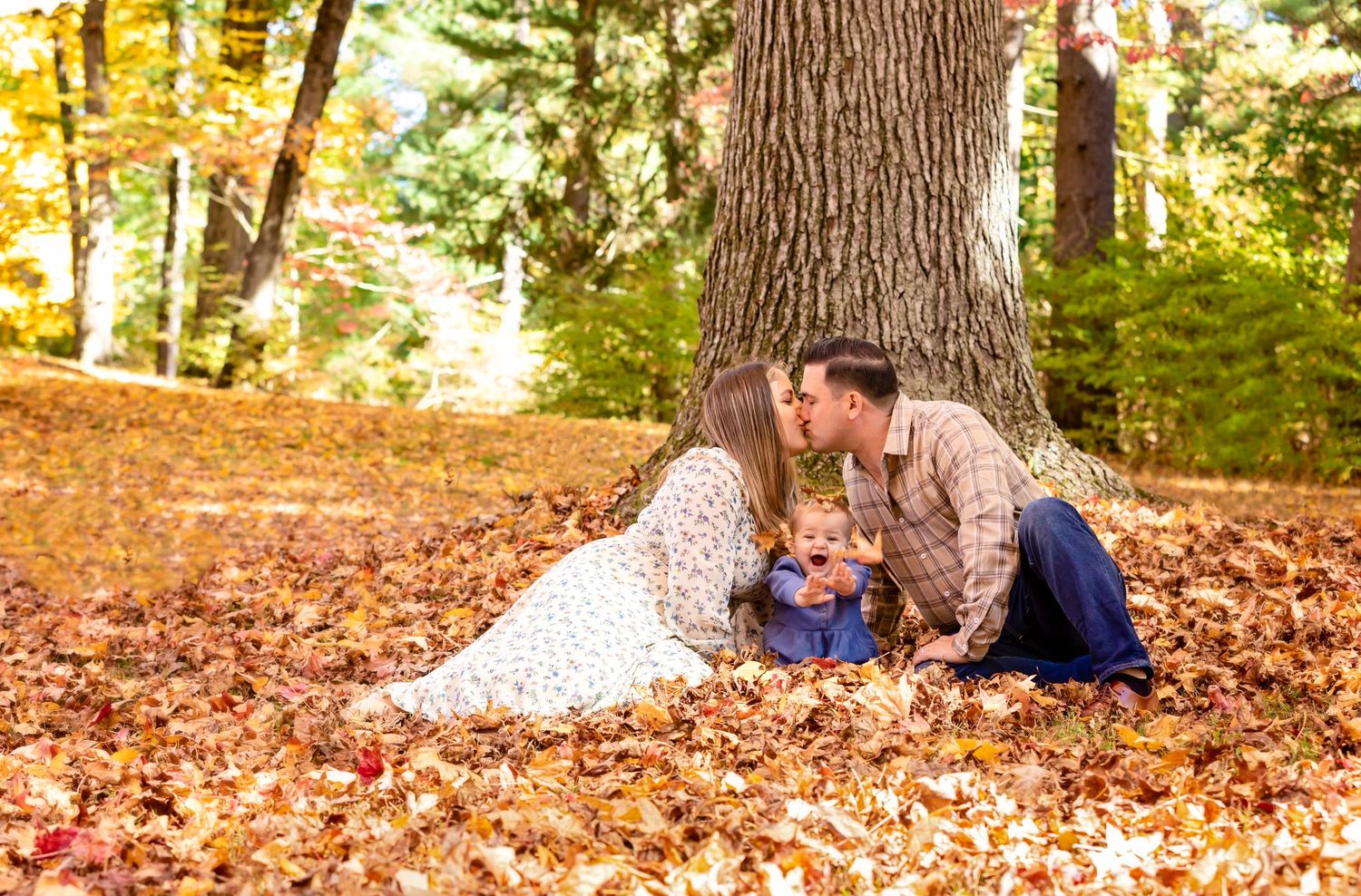 Group enjoying a warm autumn day laying on fallen leaves in a sunlit forest setting.