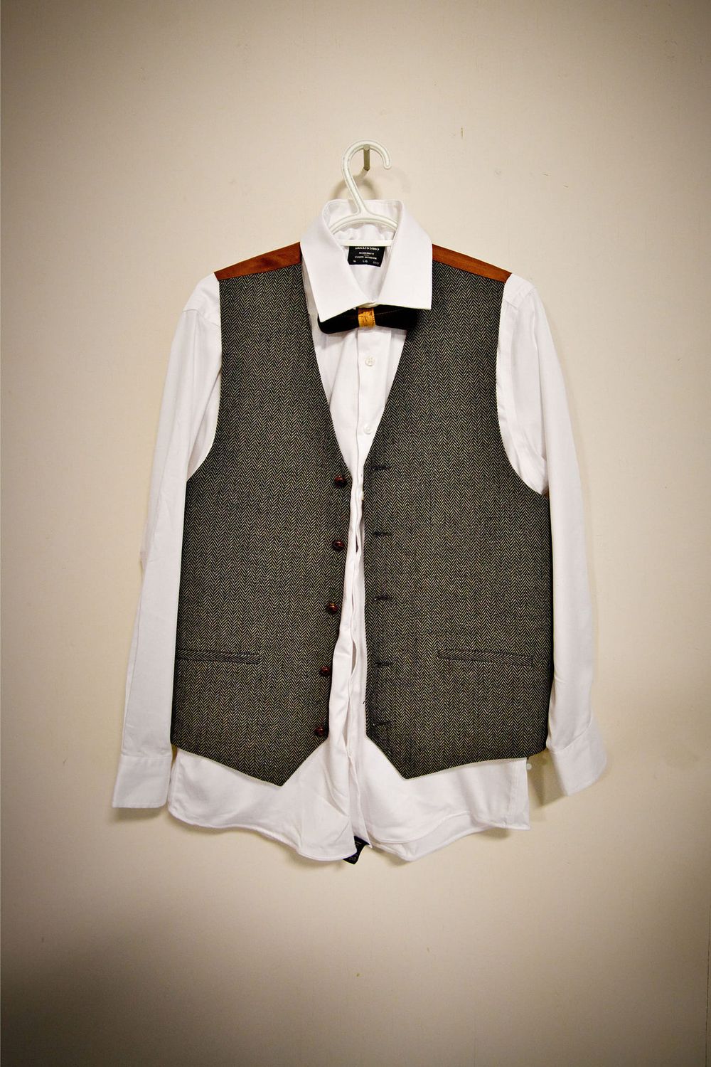 White dress shirt and grey vest formal wedding attire displayed on hangers.