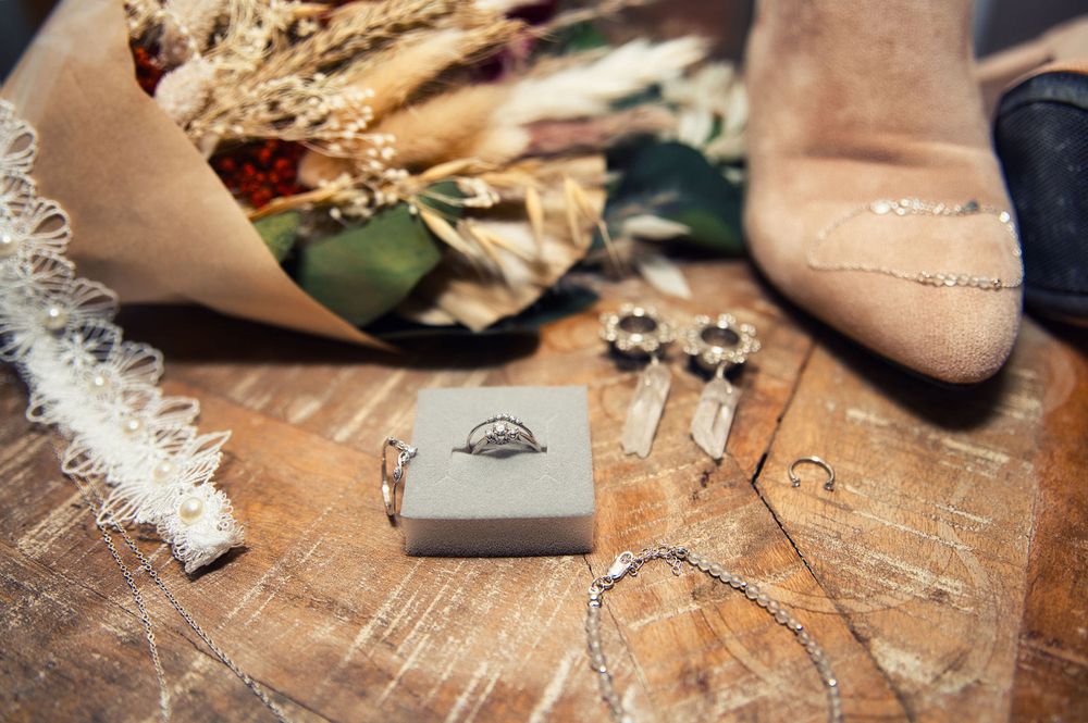 Wedding rings and jewelry details arranged on wooden surface.