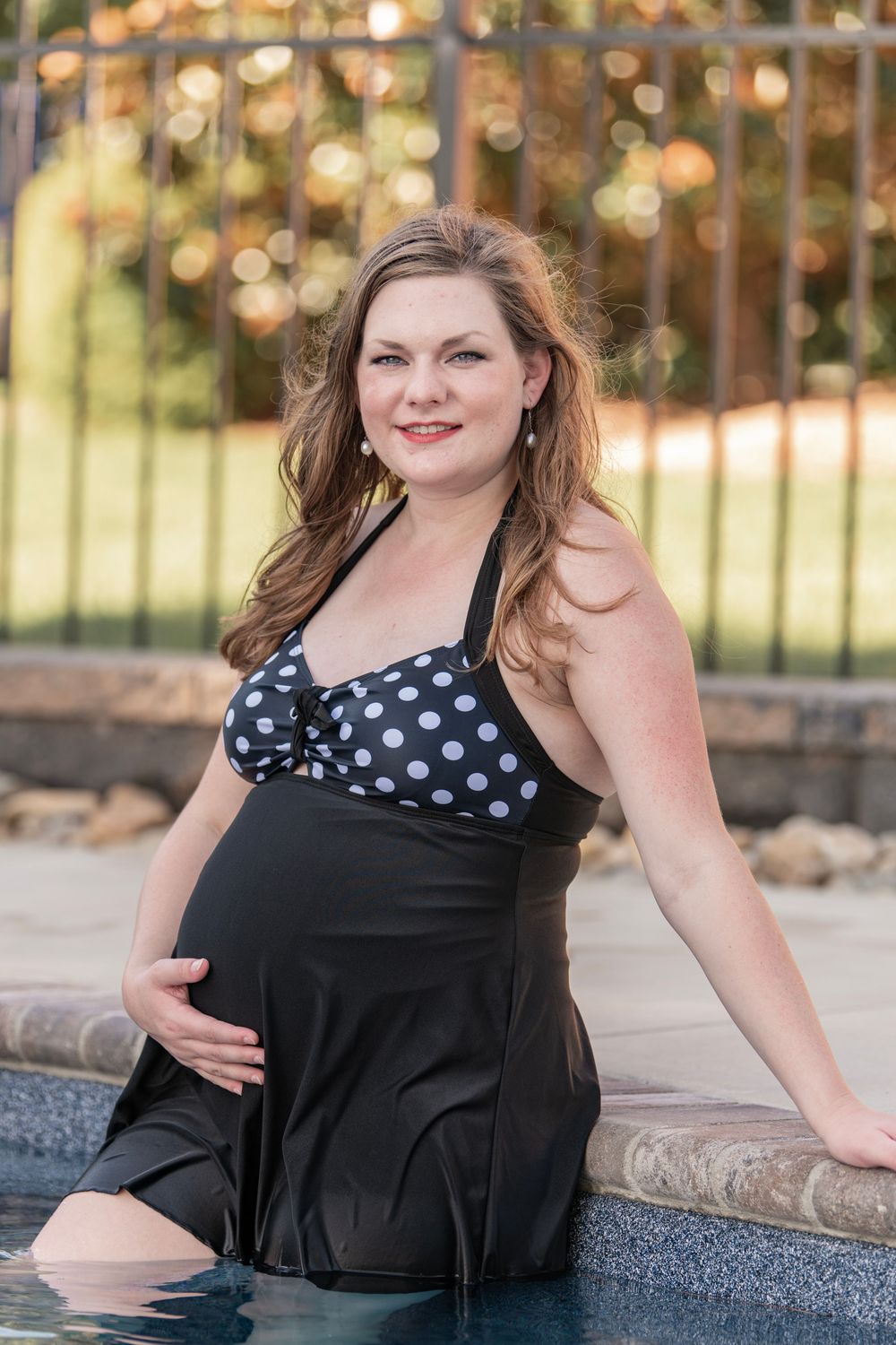 Girl poses for maternity portraits in swimming pool in Chapin, SC.