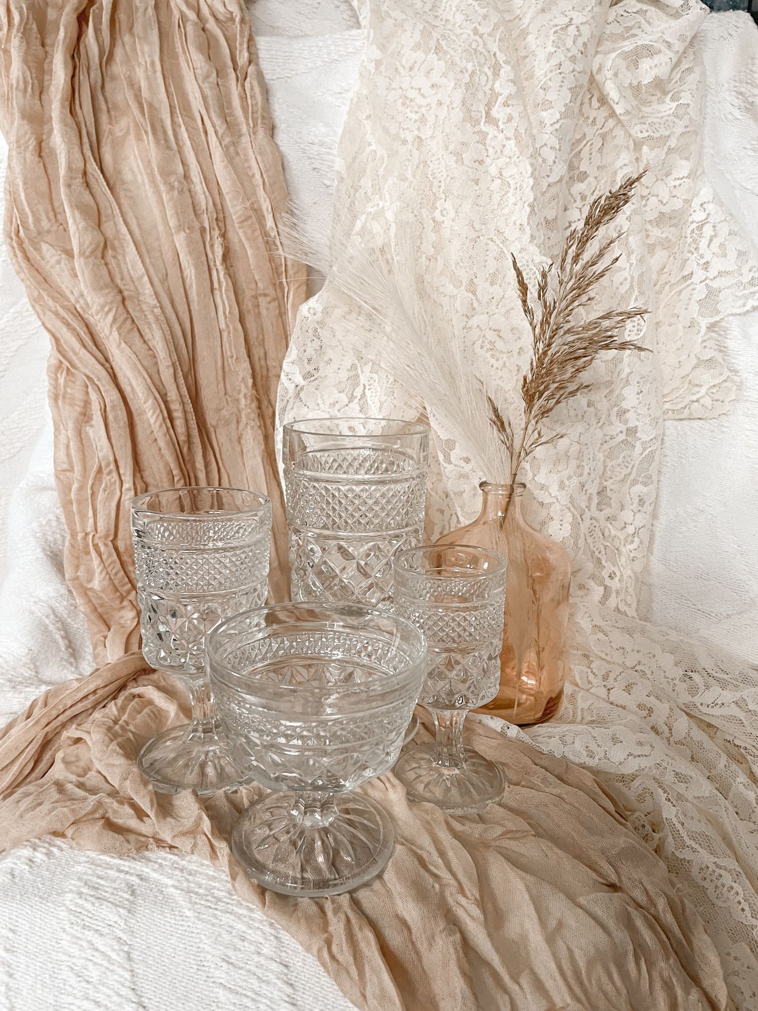 A bohemian wedding guest book with heart design and dried pampas grass decorations sits on a woven surface.