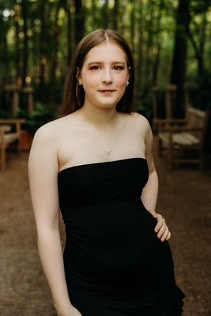 Artistic portrait series in a wooded setting with black dress against natural forest background.