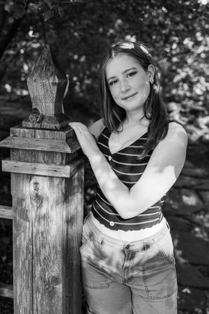 Black and white artistic portrait series showing someone leaning on a rustic wooden post outdoors.