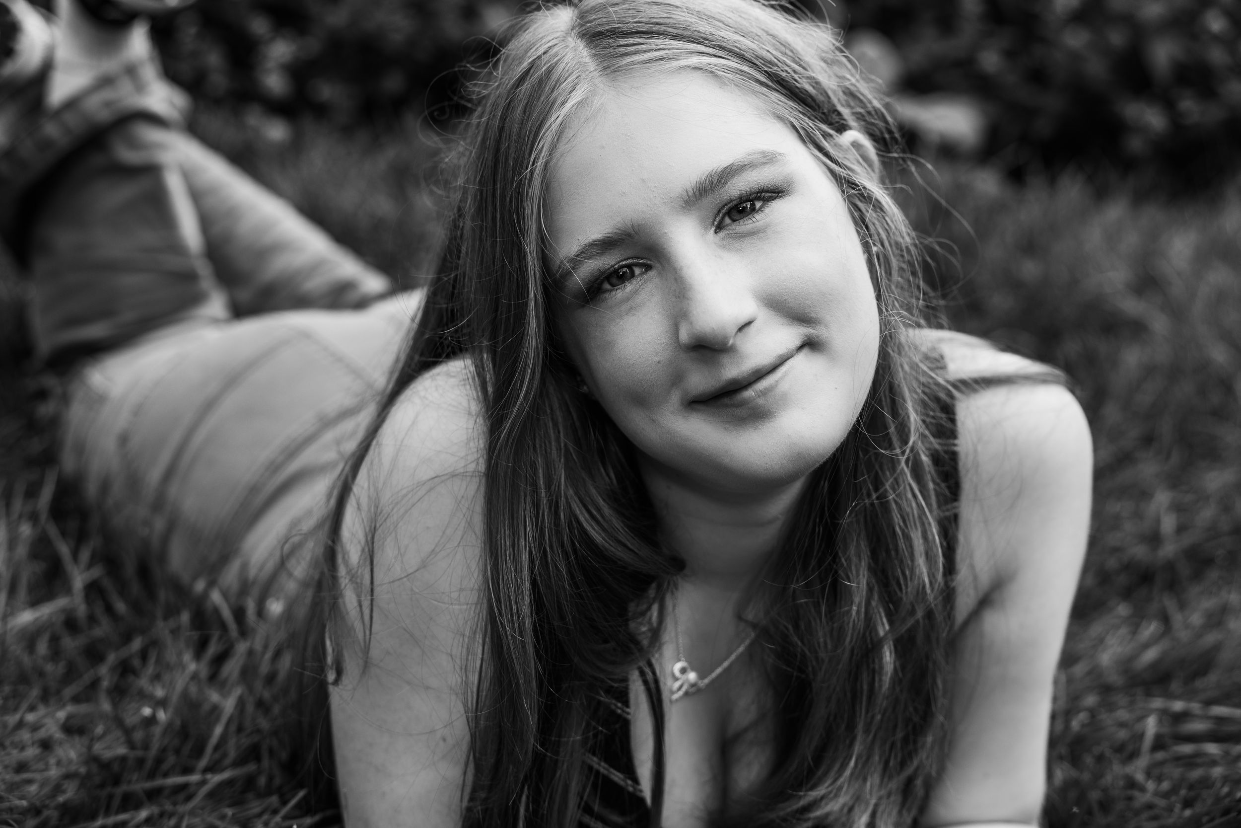Black and white photo series of person lying in grass on sunny day showing playful expressions.