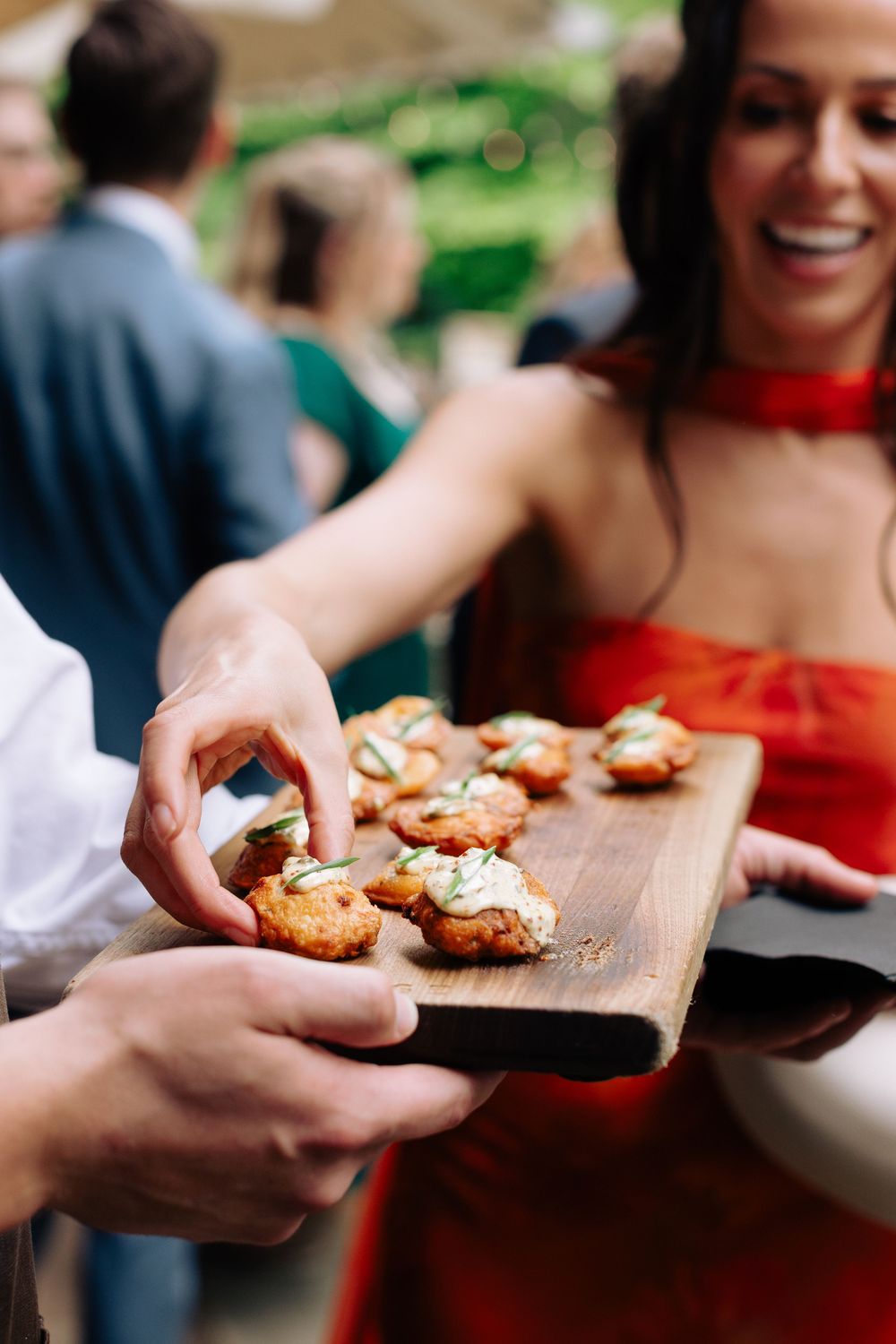 Appetizers being served on wooden boards at an outdoor wedding reception.