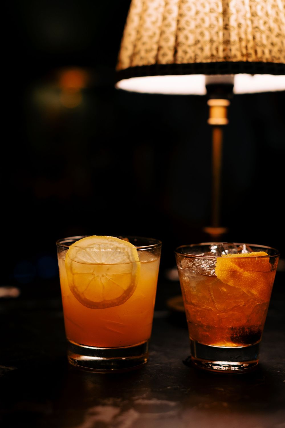 Craft cocktails with citrus garnishes displayed under warm lighting at a bar.