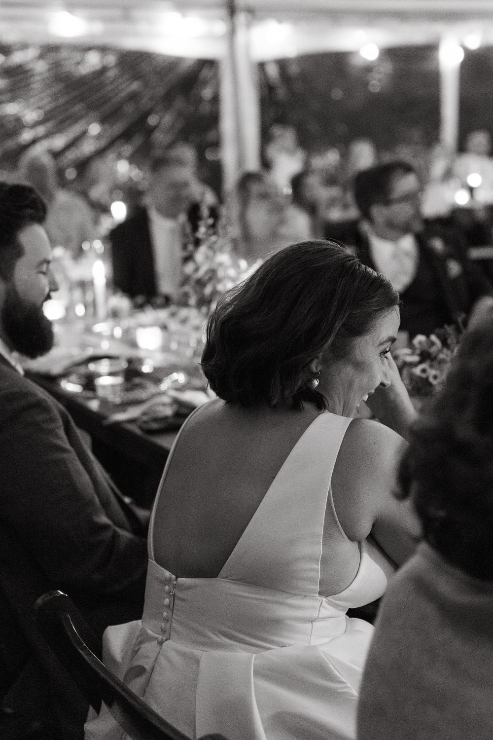 Wedding reception guests in formal attire seated at elegantly decorated tables.