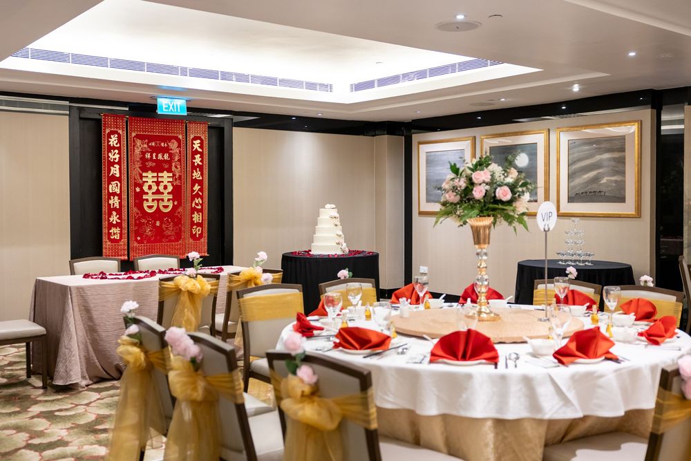 A panoramic view of an elegant banquet hall with round tables decorated with red and white linens and place settings.