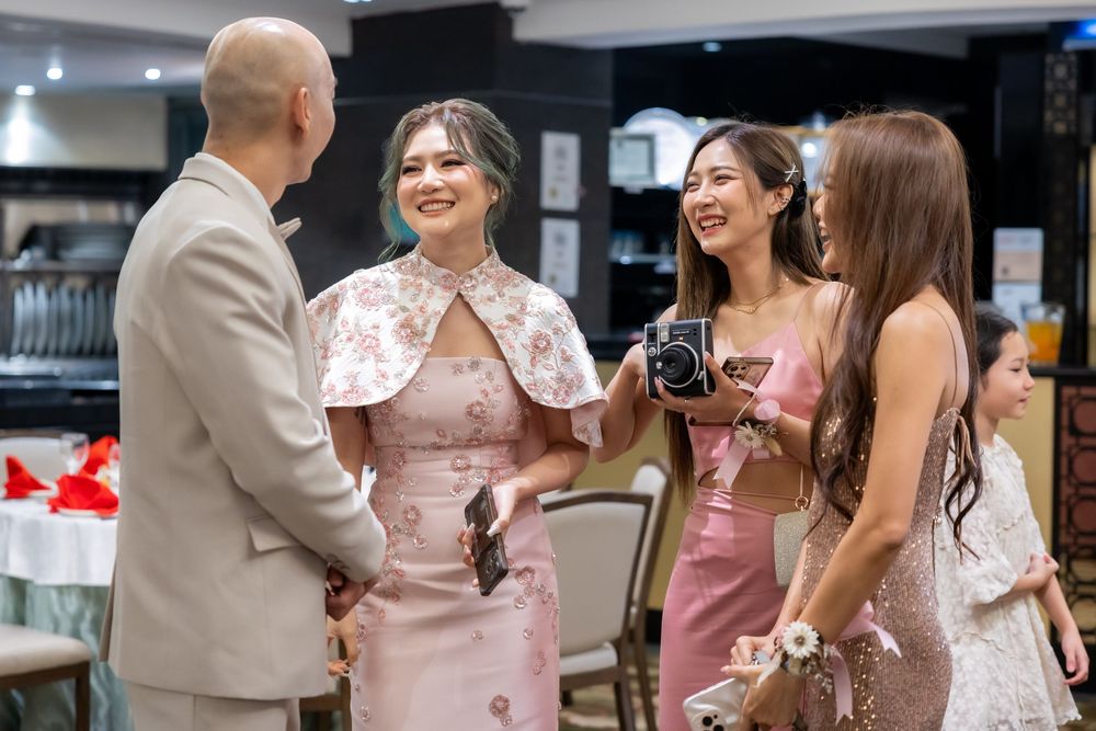 Wedding party members in pink and beige attire gather during a celebration indoors.