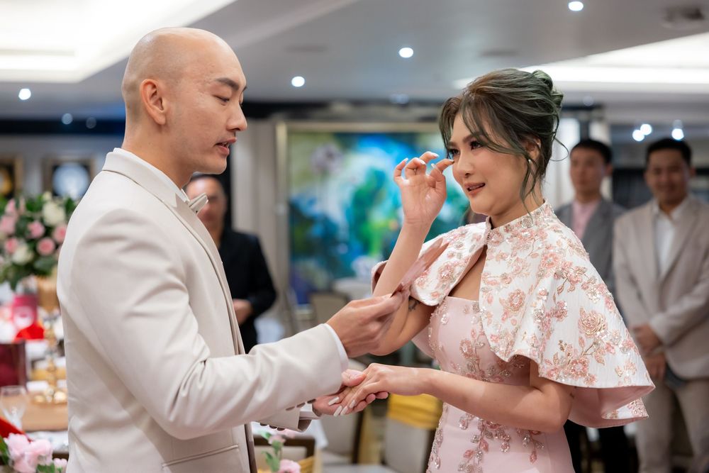 A couple sharing an emotional moment during a Chinese tea ceremony in an elegant indoor setting.