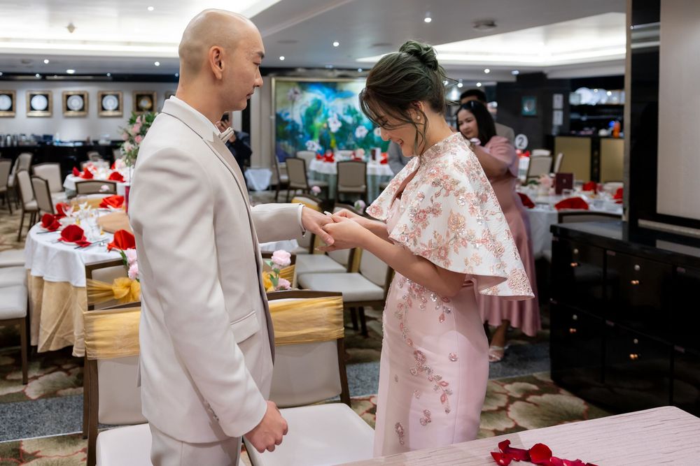 A couple dances together in formal attire at an elegant event with scattered rose petals on the floor.