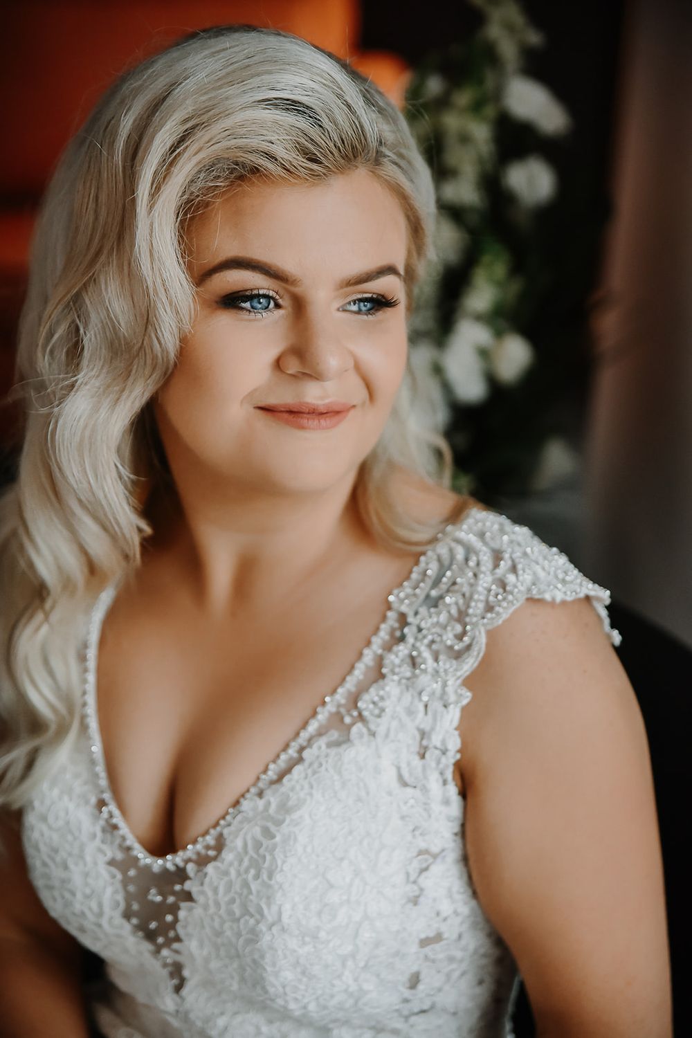 Bride wearing white lace wedding dress with delicate embellishments in soft natural lighting.