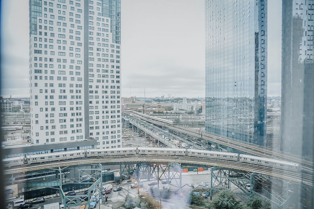 Elevated view of a modern city skyline with skyscrapers and highways converging under cloudy skies.