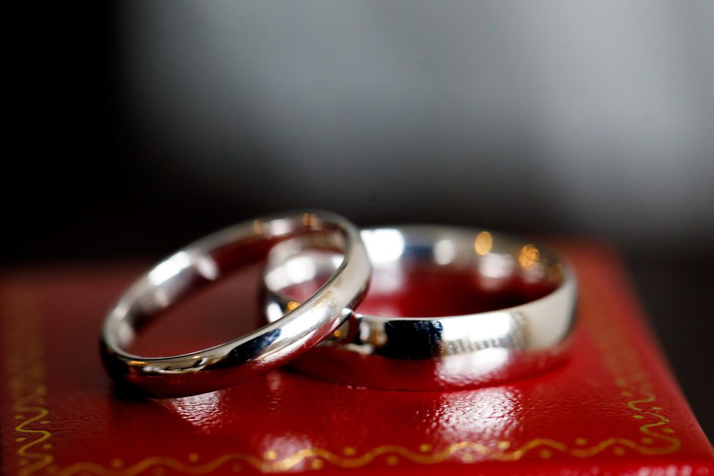 Close-up details of wedding rings displayed on a vibrant red surface with soft lighting.