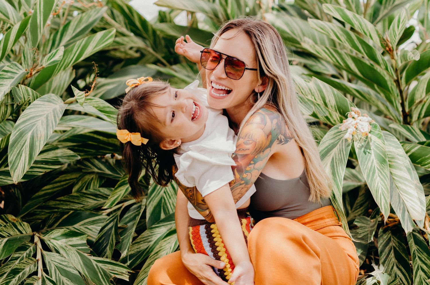A joyful moment captured against lush tropical foliage in bright sunlight.