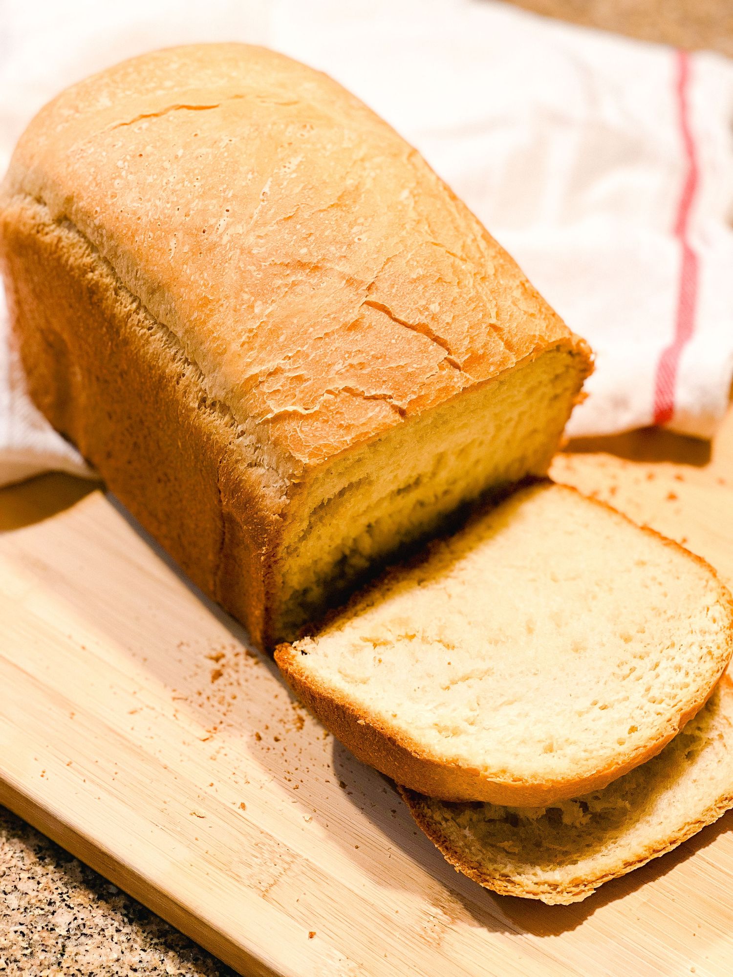 Freshly baked homemade white bread loaf sliced on a wooden cutting board.