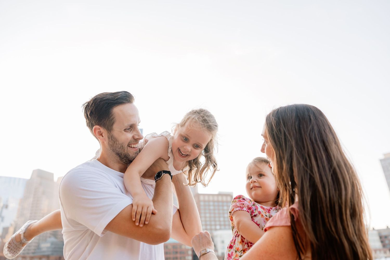 Parents and their children playing together in white shirts on a sunny day outdoors.