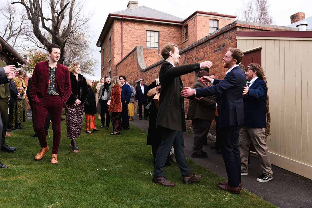 A crowd of people gathering outside a brick building on a cloudy day.